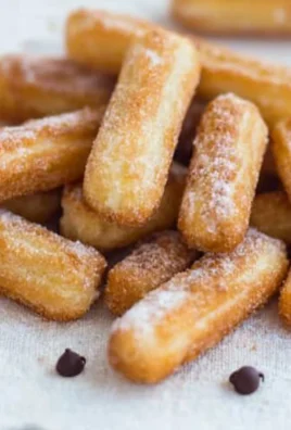 Homemade churros dusted with cinnamon sugar on a wooden plate