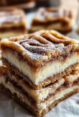 Delicious cinnamon roll bliss bars topped with creamy icing on a rustic wooden surface.