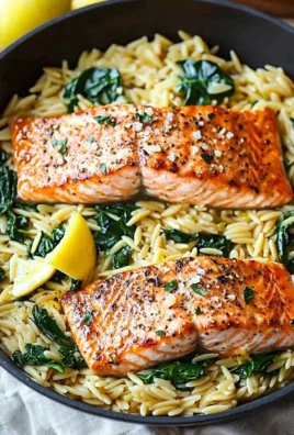 Pan-seared salmon with lemony orzo on a white plate garnished with herbs