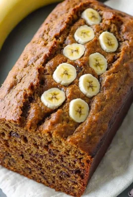A slice of healthy banana bread topped with walnuts and banana slices