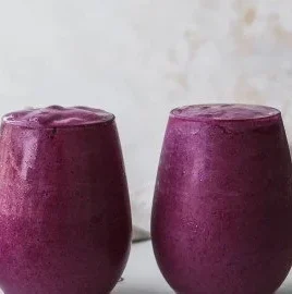 Blueberry avocado smoothie with lemon and yogurt in a glass on a table.
