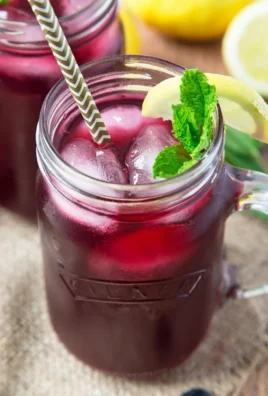 Homemade blueberry lemonade in a glass with fresh blueberries and lemons