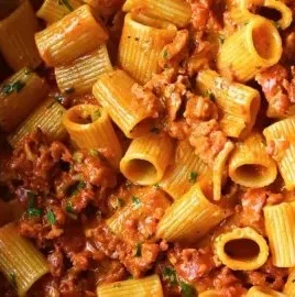 Creamy chorizo pasta dish garnished with herbs and served in a bowl.