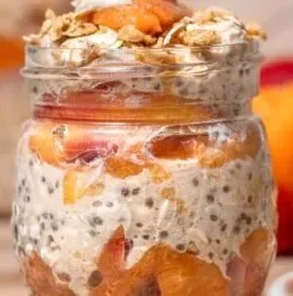 Bowl of creamy peach overnight oats topped with fresh peach slices and nuts