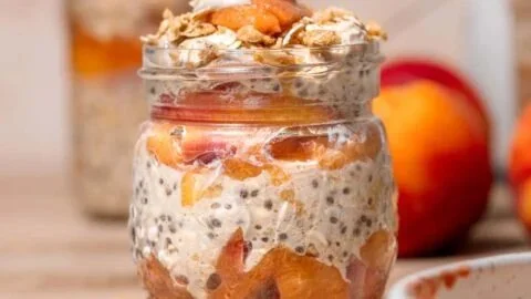 Bowl of creamy peach overnight oats topped with fresh peach slices and nuts