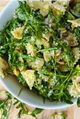 Lemon Arugula Pasta Salad served in a bowl with fresh greens and lemon slices