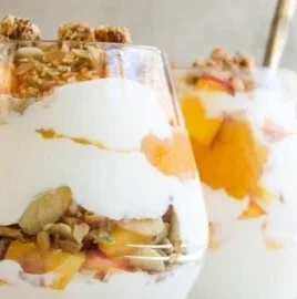 Peach Yogurt Parfait with fresh peach compote and granola in a glass.