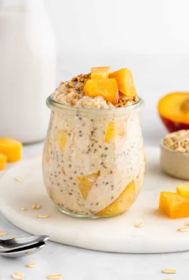 A bowl of peaches and cream overnight oats topped with fresh peaches and nuts.