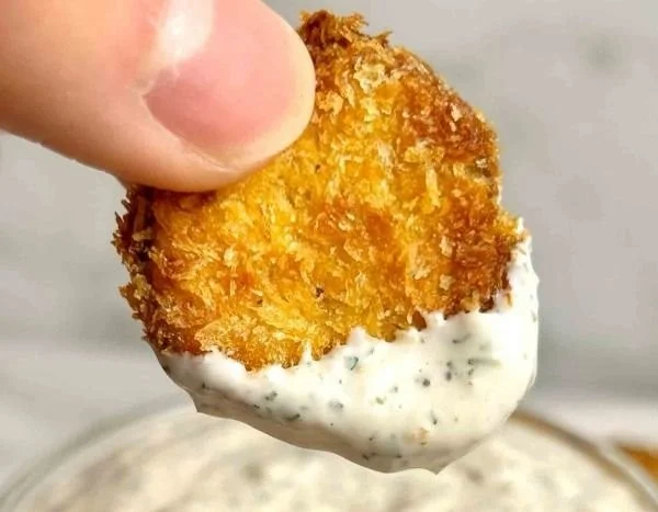 Crispy air fryer fried pickles served with dipping sauce on a plate.