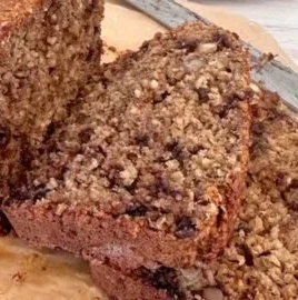 Moist banana bread made with oat flour, served on a wooden cutting board.