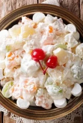 A bowl of creamy fruit salad with assorted fruits and a creamy dressing