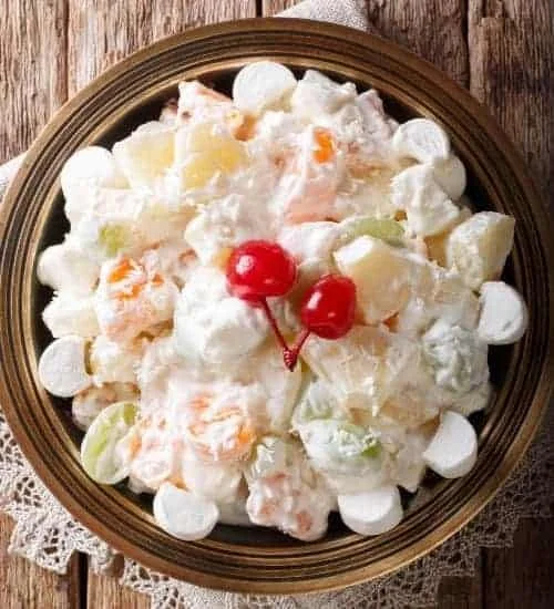 A bowl of creamy fruit salad with assorted fruits and a creamy dressing