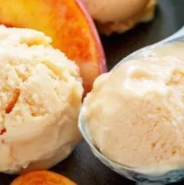 Creamy high protein peach ice cream in a bowl with fresh peach slices