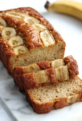 Flourless Greek Yogurt Banana Bread slice on a plate with fresh bananas