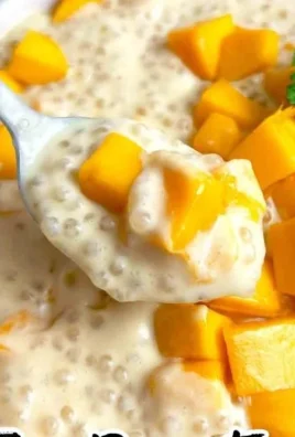 A bowl of creamy Mango Sago dessert topped with fresh mango slices and sago pearls.