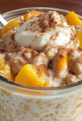 Bowl of overnight peach cobbler oatmeal topped with fresh peaches and cinnamon