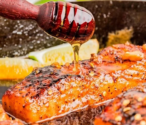 Pan-seared hot honey salmon garnished with herbs and served on a plate