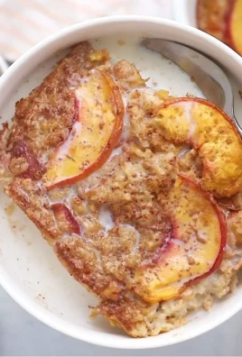 Bowl of delicious Peach Baked Oatmeal topped with fresh peach slices