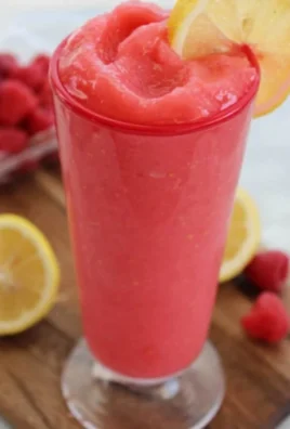 Refreshing Raspberry Lemonade Slushie in a glass with ice and fresh raspberries