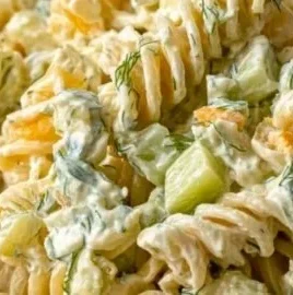 A bowl of simple dill pickle pasta salad with fresh ingredients and herbs.