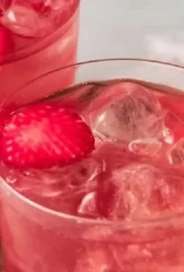 A refreshing glass of strawberry iced tea garnished with fresh strawberries and mint.