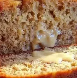 Freshly baked moist banana bread with bananas on a wooden cutting board