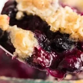 Delicious blueberry dump cake topped with fresh blueberries and whipped cream