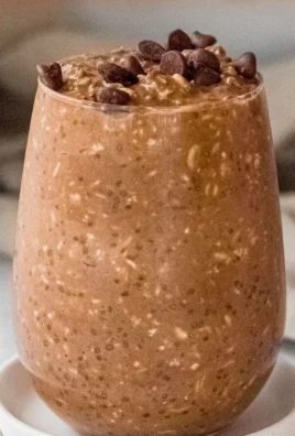 Bowl of chocolate overnight oats topped with fresh berries and nuts.