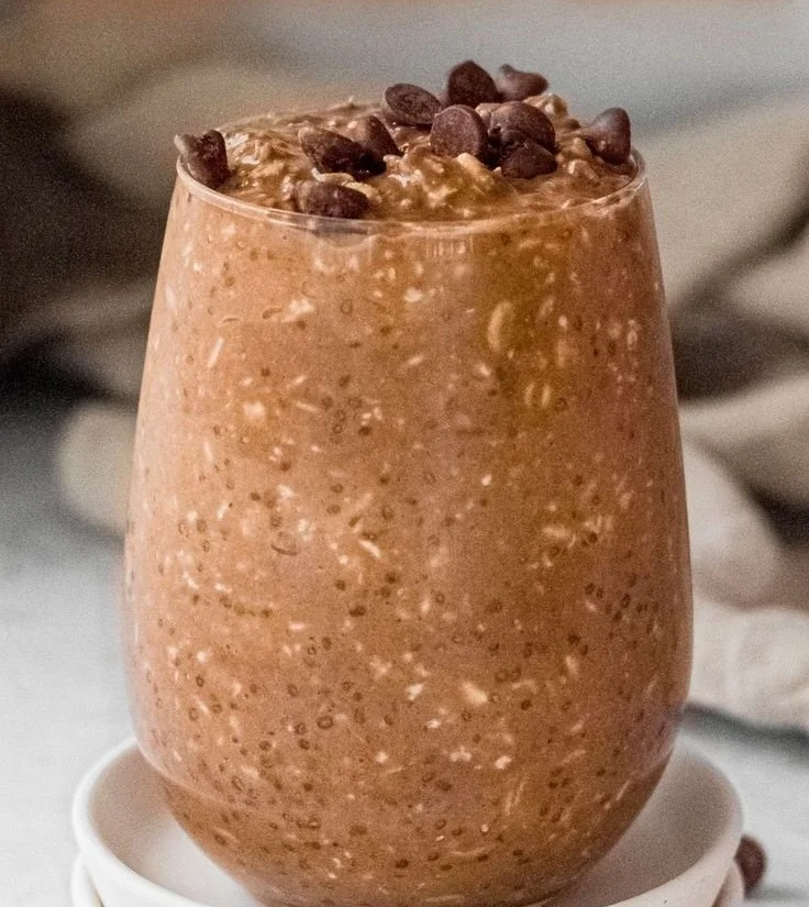 Bowl of chocolate overnight oats topped with fresh berries and nuts.