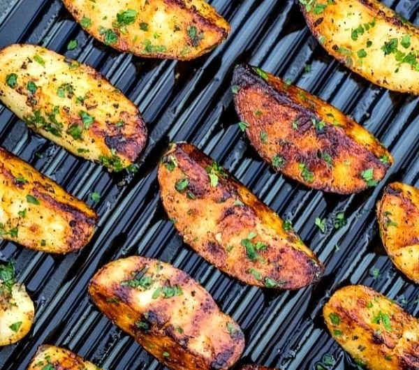 Crispy grilled potatoes served on a plate at a summer BBQ.
