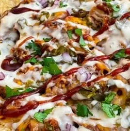 Delicious sheet pan BBQ chicken nachos topped with cheese and jalapeños.