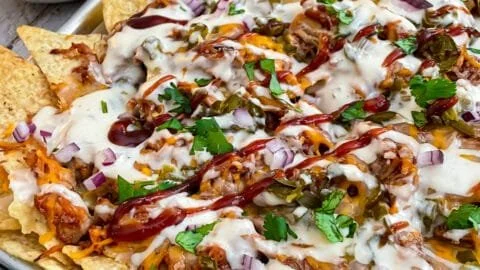 Delicious sheet pan BBQ chicken nachos topped with cheese and jalapeños.