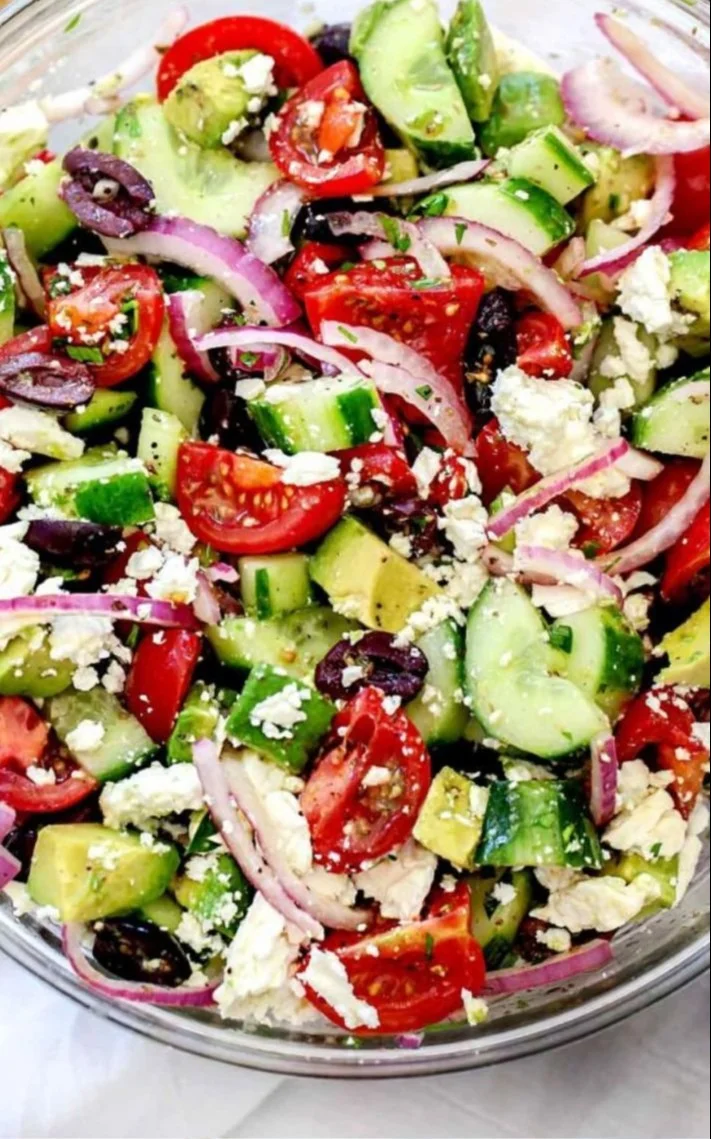 Delicious Greek salad with avocado, tomatoes, cucumber, feta, and olives.