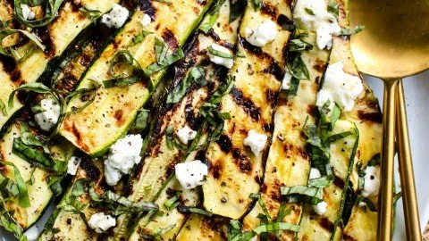 Grilled zucchini topped with goat cheese, basil, and honey on a plate