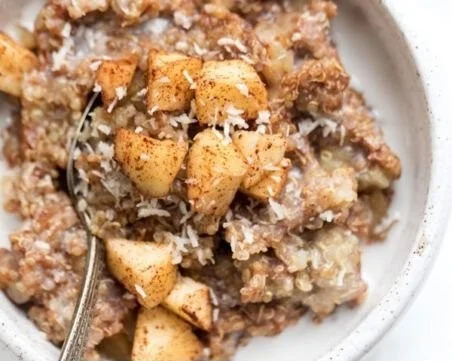 Healthy quinoa apple breakfast bowl topped with fresh apples and nuts.