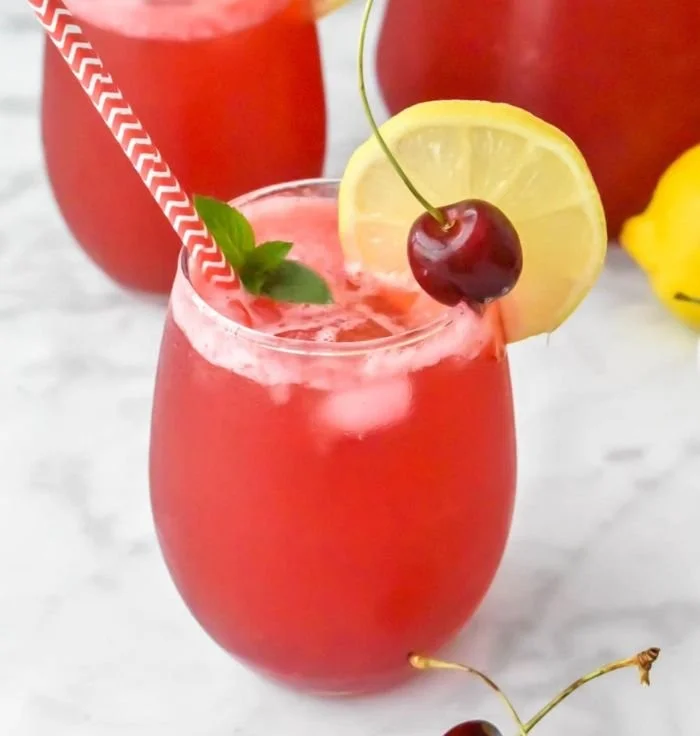 Refreshing homemade cherry lemonade served in a glass with lemon slices and cherries