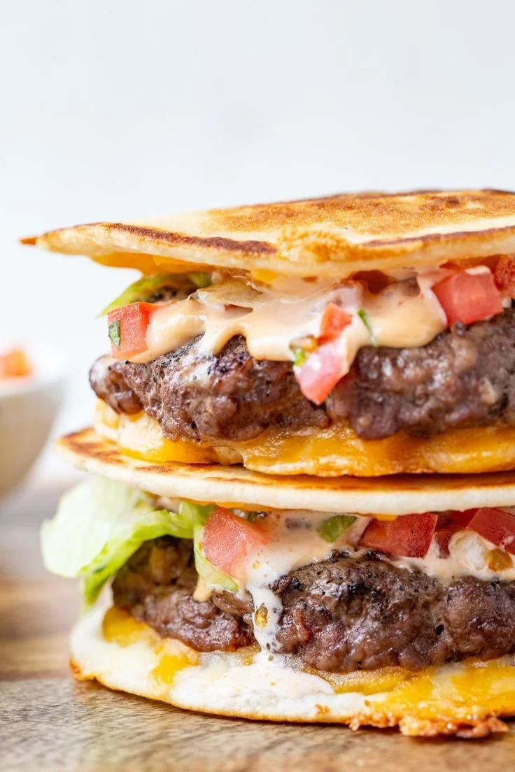 Delicious quesadilla burger with melted cheese and toppings on a plate