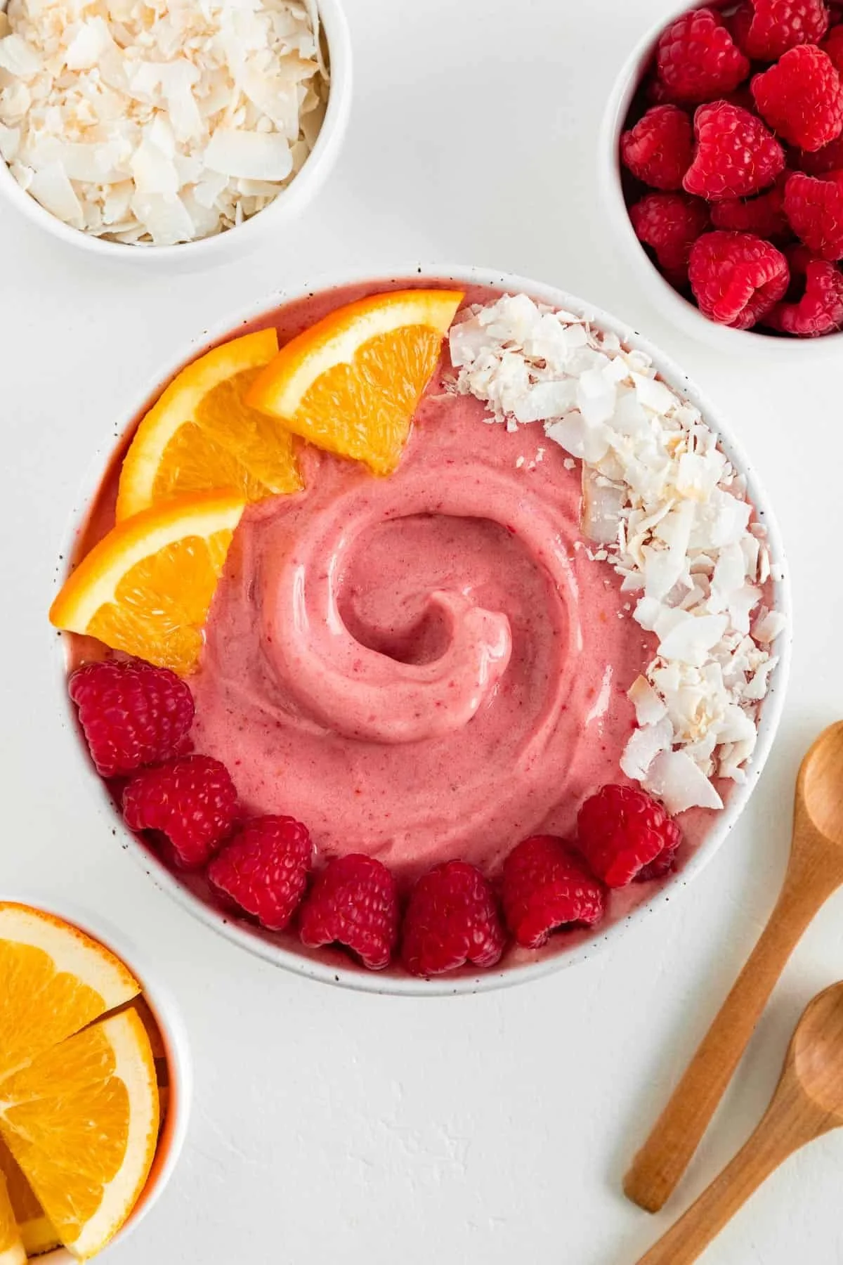 Bright Raspberry Orange Smoothie Bowl garnished with fresh fruits and nuts.