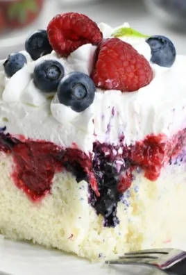 Delicious Summer Berry Poke Cake topped with fresh berries and whipped cream