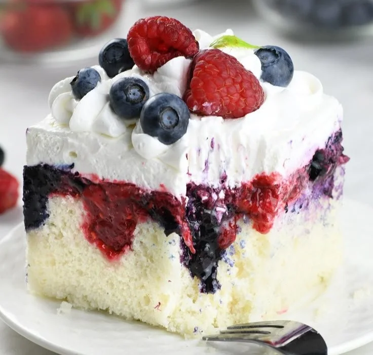 Delicious Summer Berry Poke Cake topped with fresh berries and whipped cream