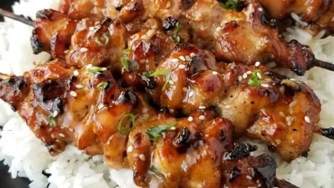 Grilled teriyaki chicken skewers garnished with vegetables.